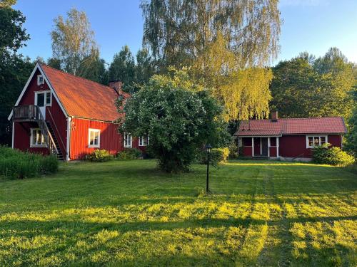 a red house with a tree in the yard at Charming Forest Retreat, 15 Min from Mariefred in Nykvarn