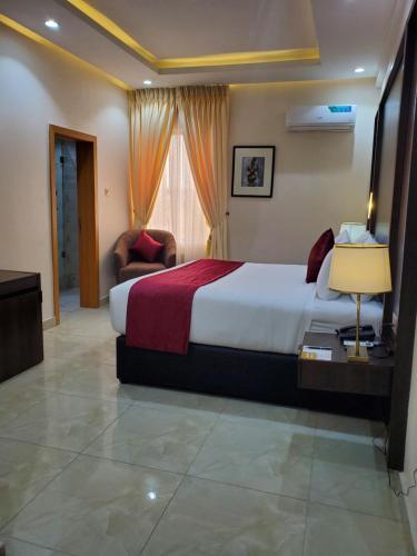 Executive Hotel and Suites في إيكيجا: غرفة فندق مع سرير وكرسي