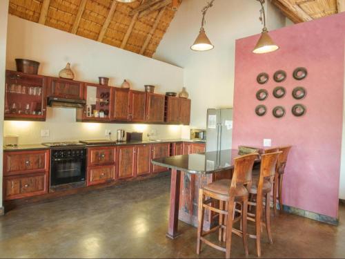 una cocina con armarios de madera, mesa y sillas en Kokobela Lodge, en Phalaborwa