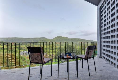 two chairs and a table on a balcony with a view at SaffronStays Bonsai in Wādhiware