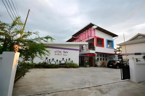 a white and pink building with a parking lot at Na-Rak-O Resort in Chiang Rai