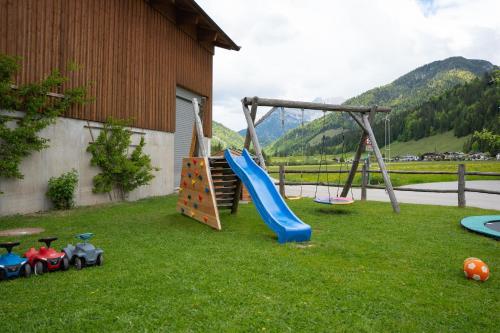 a playground with a slide and play equipment in a yard at Ferienwohnungen Recherhof in Hochfilzen