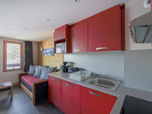 - une cuisine avec des placards rouges, un évier et un canapé dans l'établissement Appartement 6 pers, bien-être, accès pistes, animaux OK - FR-1-181-2380, à La Plagne Tarentaise