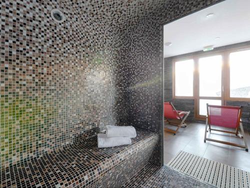 La salle de bains est pourvue d'une douche et de mosaïques. dans l'établissement Spacieux Appartement Rénové avec Balcon, Accès Ski au Pied et Espace Bien-Être - FR-1-181-1929, à La Plagne Tarentaise