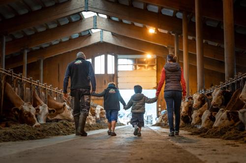 a family walking through a barn with cows at Ferienwohnungen Recherhof in Hochfilzen