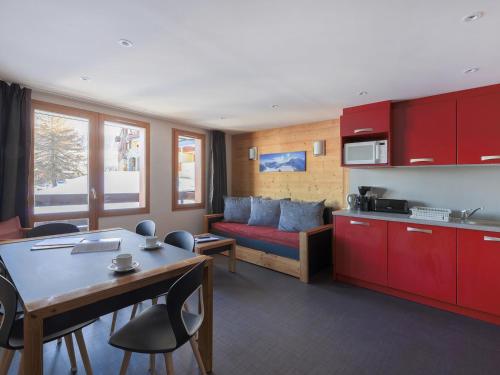 Il comprend une cuisine et un salon avec des placards rouges et un canapé. dans l'établissement Appartement Rénové· 42m²· Ski aux Pieds· Balcon Est· Sauna & Hammam· Parking Gratuit - FR-1-181-1964, à La Plagne Tarentaise