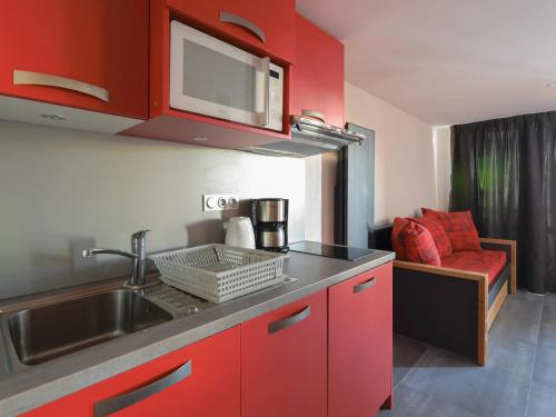 - une cuisine avec des placards rouges, un évier et un canapé dans l'établissement Studio rénové 3 pers · Proche pistes · Balcon · TV · Animaux admis - FR-1-181-1993, à La Plagne Tarentaise