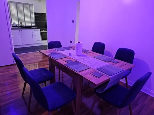 a dining room table with blue chairs and a candle on it at Barnsley cozy home 