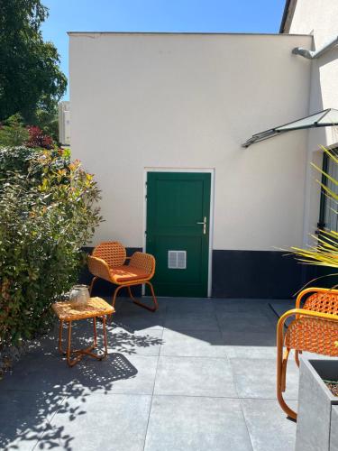 a patio with two chairs and a green door at Hôtel Échappée en Baie - Parking privé gratuit dont forfaits bornes électriques réservable in Saint-Valery-sur-Somme