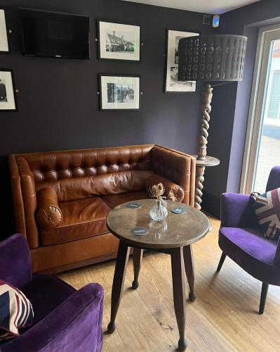 a living room with a leather couch and a table at The Kings Head Inn, Norwich - AA 5-Star rated in Norwich