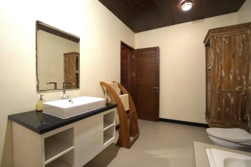 a bathroom with a sink and a toilet and a mirror at Ocean Terrace Suite And Spa Luxury in Nusa Penida