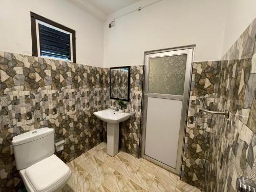 a bathroom with a toilet and a sink and a shower at Sea Waves Home Stay in Talalla