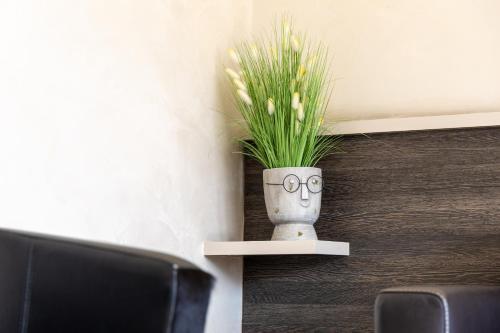 a vase with eyes on it sitting on a shelf at Hotel Castel in Sion