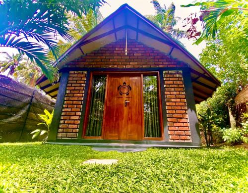 a small house with a door in the grass at Ritter Kreuz Cabana Resort in Tangalle