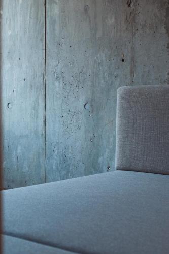 a white bed in front of a concrete wall at Alternest Kamakura in Kamakura