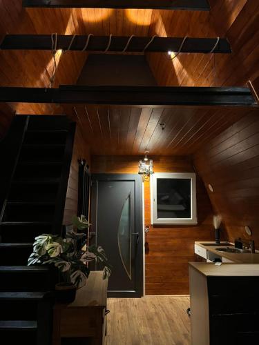 Una sala de estar con una puerta negra y paredes de madera. en le moodeng, en Villampuy