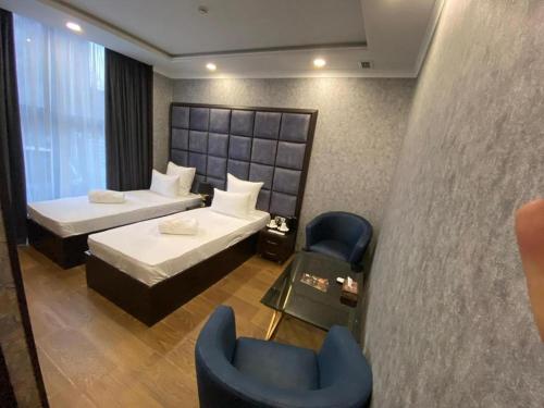 una camera d'albergo con due letti e una sedia di VIAGGIO Hotel BY VG a Yerevan