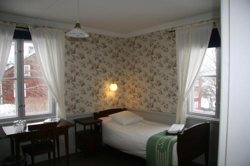 a small bedroom with a bed and two windows at Sätra Brunn Hälsobrunn in Sätrabrunn