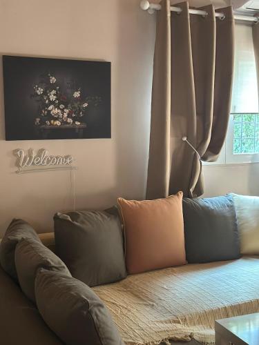a couch with pillows in a living room with a window at Rest & Reveal apartments in Vari