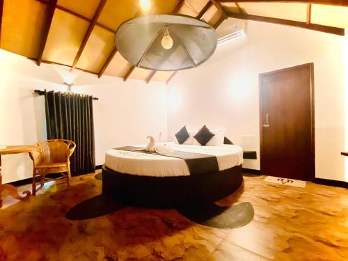 a bedroom with a bed with a table and a chandelier at Ritter Kreuz Cabana Resort in Tangalle