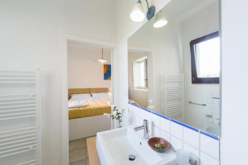 a white bathroom with a sink and a bedroom at Kalinifta - Io parto Io arrivo in Tricase