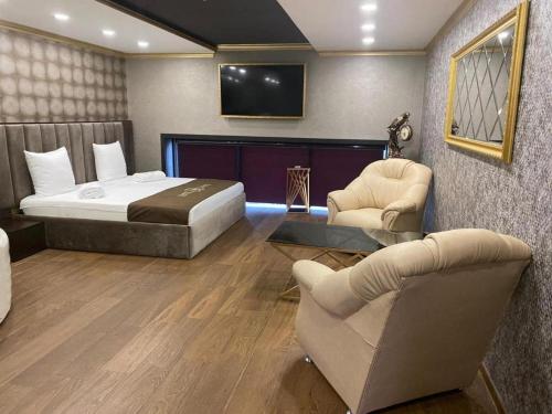 una camera con letto, TV e sedie di VIAGGIO Hotel BY VG a Yerevan