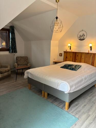 une chambre avec un grand lit et une chaise dans l'établissement Chez Yolande, à Nothalten