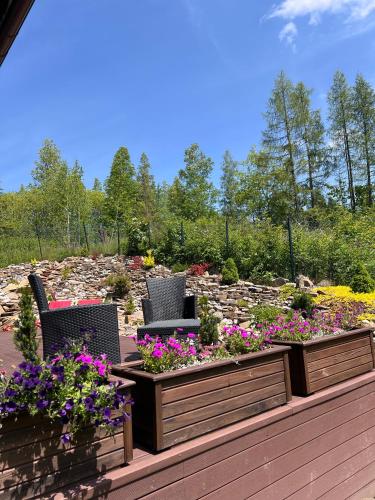 a garden with two chairs and flowers on a deck at Willa Skała in Kościelisko