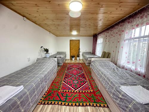 a room with two beds and a rug at Guest house Ayperi in Bokonbayevo