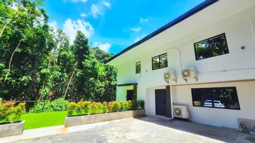 a white house with a balcony with trees at Kiddie Hostel 13A1-Kids and pets friendly in Kababae