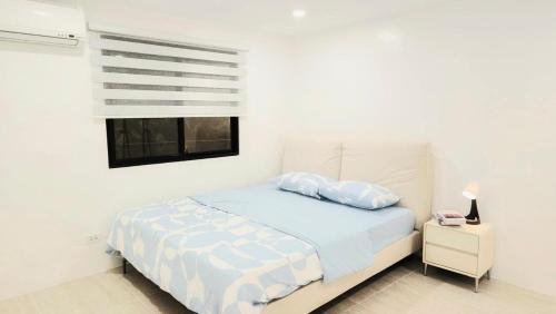 a white bedroom with a bed and a window at Kiddie Hostel 13A1-Kids and pets friendly in Kababae