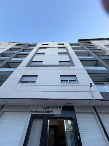 a tall building with a sign on the side of it at Appart Résidence Sabrin in Fnidek