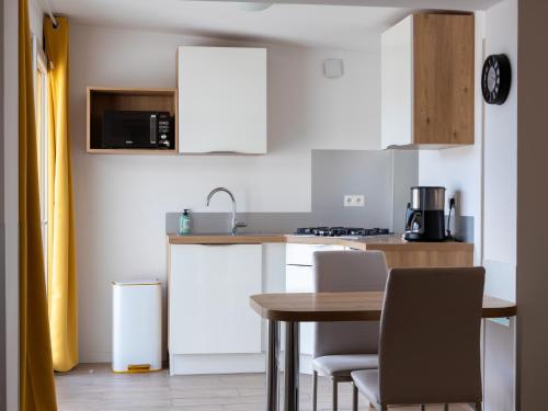 une cuisine avec une table et des chaises et un micro-ondes dans l'établissement Ty Bihan by Madame Est Servie, à Pleumeur-Bodou