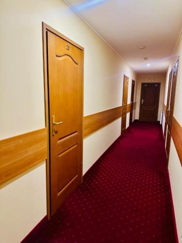 a hallway with a wooden door and a red carpet at Zajazd KAMA KOWALSKI in Skępe
