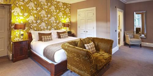 a bedroom with a large bed and a chair at Fonab Castle Hotel in Pitlochry