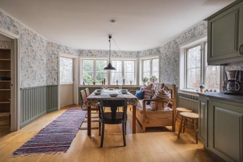 a kitchen with a table and chairs and windows at Charming Forest Retreat, 15 Min from Mariefred in Nykvarn