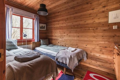 two beds in a room with wooden walls at Charming Forest Retreat, 15 Min from Mariefred in Nykvarn