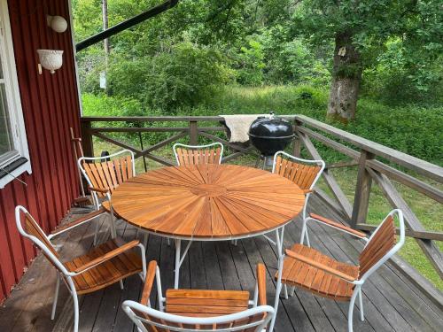 a wooden table and chairs on a deck with a grill at Charming Forest Retreat, 15 Min from Mariefred in Nykvarn