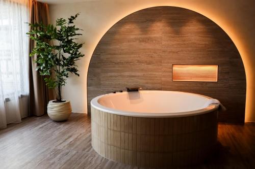 a bath tub in a bathroom with a brick wall at Van der Valk Hotel Vianen - Utrecht in Vianen