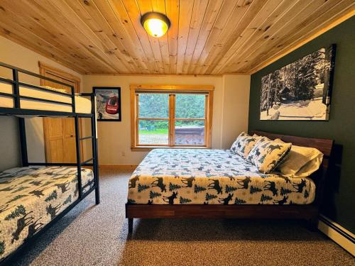 a bedroom with two bunk beds and a window at Ski Chalet 6 min to Sunday River - Hot Tub, Home Theater, Game Room, Fire Pit - Sleeps 12 in Bethel