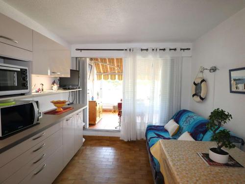 un salon avec un canapé et une cuisine dans l'établissement Appartement T2 avec terrasse et parking à 350m de la plage, proche commerces. - FR-1-307-217, au Grau-du-Roi