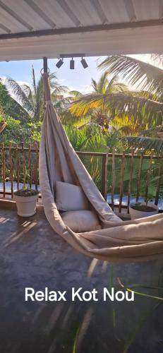 a hammock on a patio with palm trees at Kot Nou - Kwizine Mama Manze Lakaz in Mahébourg