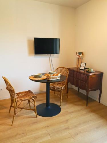 a room with a table and chairs and a television at Proche métro B et Hopital Lyon sud in Pierre-Bénite