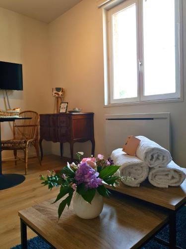 a room with a table with towels and a vase of flowers at Proche métro B et Hopital Lyon sud in Pierre-Bénite