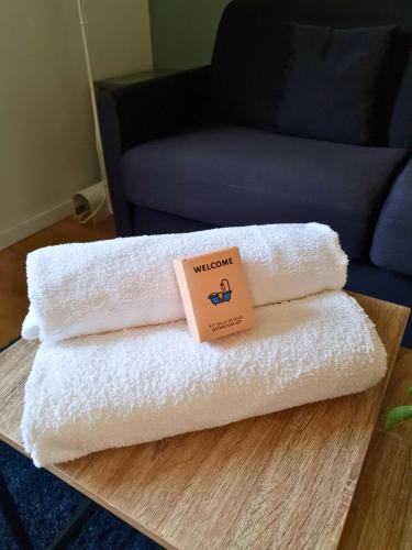 a stack of towels on a table with a sign on it at Proche métro B et Hopital Lyon sud in Pierre-Bénite