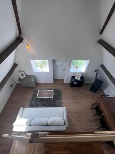a living room with a white couch and two windows at The Cotton Suites B&B in Deerlijk