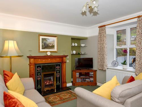 a living room with a fireplace and a tv at Molly's Cottage in Glenridding