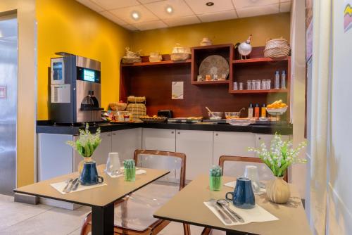 deux tables et chaises dans une cuisine aux murs jaunes dans l'établissement Accueil Hôtel Paris Pigalle Montmartre, à Paris