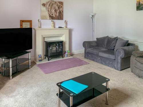 a living room with a couch and a fireplace at Bonshawside Farmhouse in Kirtlebridge