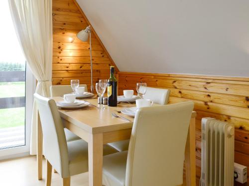 a dining room table with white chairs and a bottle of wine at Glenlivet View in Auchnastank